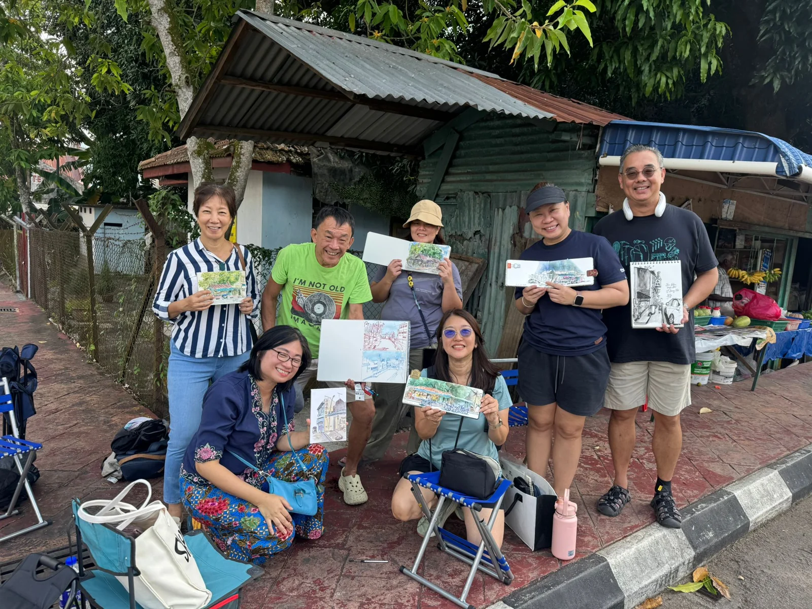 A group sharing their paintings outdoors